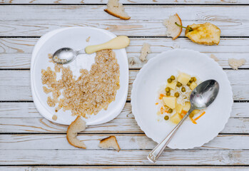 Leftovers from soup, porridge, uneaten food with bread crumbs lie on plates after a person on a wooden table. Photography, concept, wooden background.