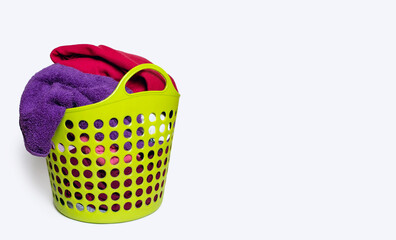 Dirty clothes in a plastic green laundry basket on a white isolated background. Housekeeping and...