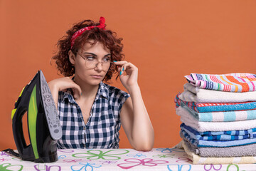 A girl with glasses glances at some ironed towels. Curly hair.