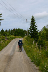 Einsamer Pilger unterwegs auf dem Pilgerweg St. Olavsweg, Gudbrandsdalsleden. Diese Schotterstraße liegt am Mjøsa kurz vor Hamar, Provinz Innlandet in Norwegen.