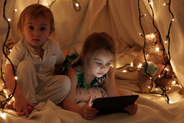 children sit in the hall and look at the tablet