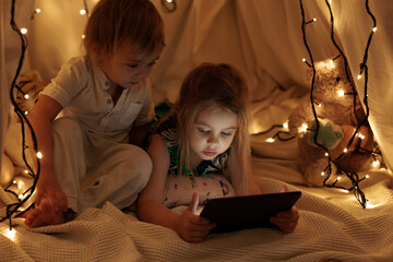 children sit in the hall and look at the tablet