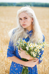 Fototapeta na wymiar portrait of a young blonde girl with a bouquet of chamomile in a field
