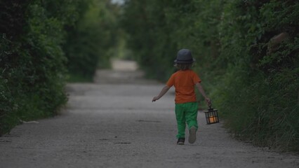 Single little child holding a lamp walk, run on empty rural road, fearful dark