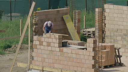 Worker place the bricks on top of each other, measure to make big building