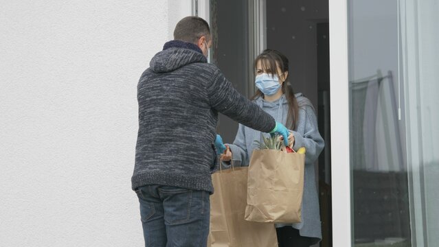 Home Delivery, Man With Mask  Give Groceries To Woman At Door