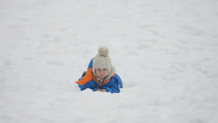 Fototapeta na wymiar Portrait of little baby child laying down in snow, white landscape nature