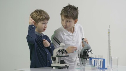 Little scientists using laboratory glassware and microscope