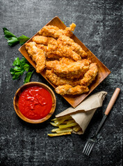 Chicken strips with parsley, French fries and tomato sauce in bowl.