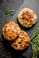 Cutlets on a black stone Board with thyme.