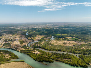 Sunny day aerial view of two river confluence passing by town full of vegetation on plan terrain.
