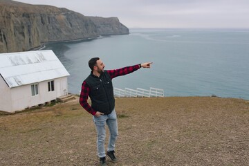 
Side view of a tourist pointing with his hand in the right direction.
Man traveler explores the area. Healthy lifestyle and outdoor activities near the sea.