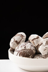 Chocolate chip cookies with cocoa and powdered sugar on a plate on a black background.