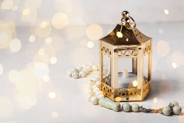 Muslim lantern with tasbih on light background with space for text. Ramadan celebration