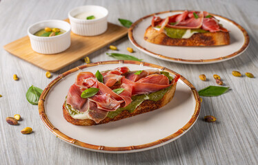 Desayuno de tostada con jamón serrano, pistacho y crema de queso feta. 