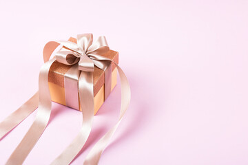 Festive gift box with a satin ribbon bow on a lilac background. Happy Valentine's Day, Mother's Day and birthday greeting card.