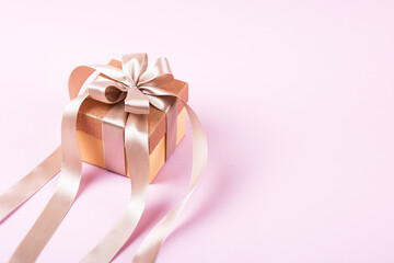 Festive gift box with a satin ribbon bow on a lilac background. Happy Valentine's Day, Mother's Day and birthday greeting card.