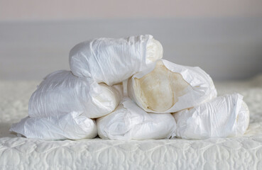 stack some many used disposable baby diapers isolated on gray carpet floor or bed in small trash...