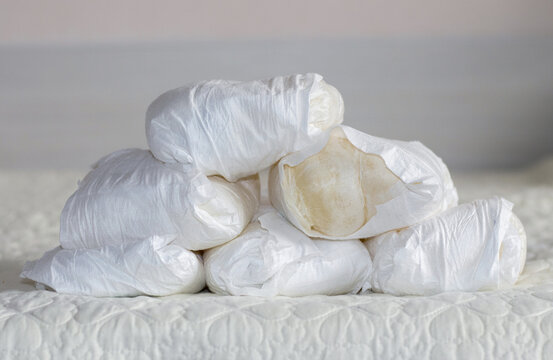 stack some many used disposable baby diapers isolated on gray carpet floor or bed in small trash bin can conceptual photography.toddler infant newborn diaper in pyramid or chaotic thrown down
