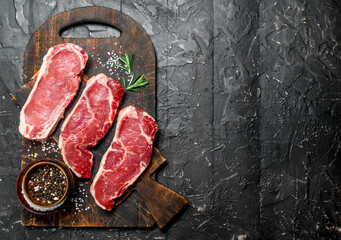 Raw marbled beef steaks with salt and spices.