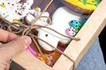 easter gingerbread cookies simple pattern repetitive shape rabbit bunny egg and sweet bread.cookie tasty eggs isolated with tulips on baking paper brown color spring is coming.woman hand open box rope