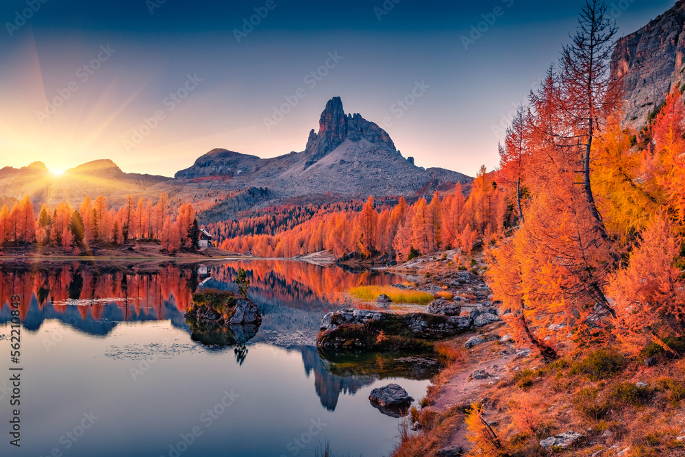 Wall mural first sunlight glowing hills of federa lake. spectacular sunrise in dolomite alps with orange larch 