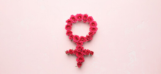 Symbol of woman made of rose flowers on light pink background. Concept of feminism