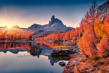 First sunlight glowing hills of Federa lake. Spectacular sunrise in Dolomite Alps with orange larch trees on the shore. Colorful morning scene of Italy, Europe. Beauty of nature concept background..