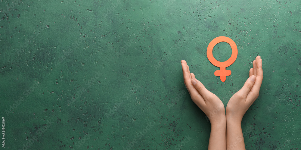 Wall mural female hands with symbol of woman on green background with space for text. concept of feminism