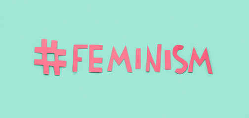 Paper word FEMINISM with hashtag on turquoise background