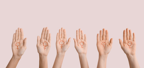 Many female hands with drawn symbols of woman on their palms against light background. Concept of...