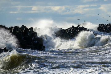 Coastal storm in the Baltic Sea, big waves crash against the harbor breakwater, breaking wave