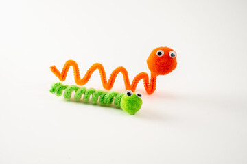 googly eyed pom pom pipe cleaner orange wriggly worm green caterpillar funny character childs toy hand made isolated on a white background