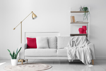 Interior of light living room with shelving unit, sofa and lamp