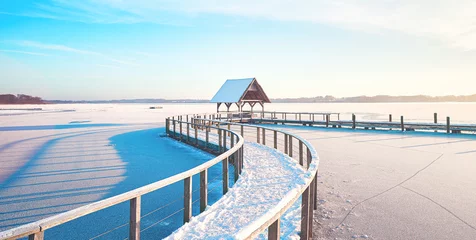 Fototapeten Frozen lake in winter with footbridge on sunny day. High quality photo © Florian Kunde
