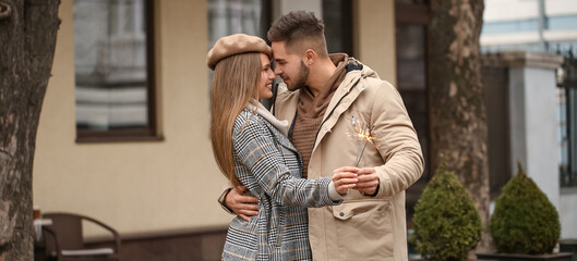 Happy young couple with sparklers walking outdoors