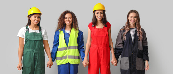 Group of female workers holding hands on grey background. Concept of feminism