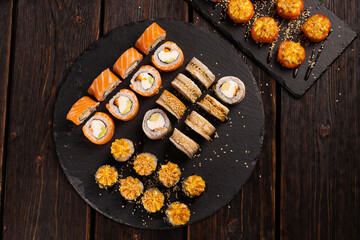 Large sushi set from top on black background. An assortment of various maki nigiri and rolls seafood soy sauce
