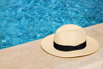 Summer hat on edge of swimming pool, closeup