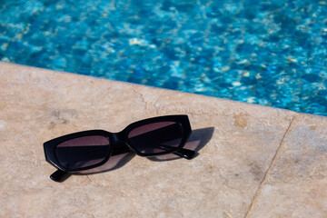 Sunglasses on edge of swimming pool, closeup