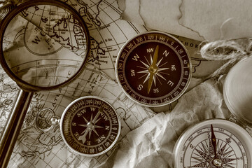 Fototapeta na wymiar Different compasses and magnifier on world map