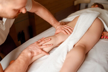 Obraz na płótnie Canvas Masseur massaging woman's leg in spa salon