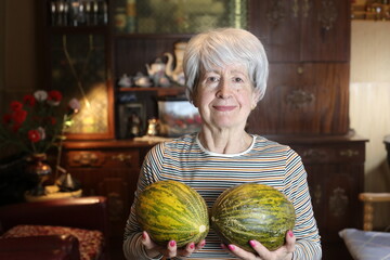 Fototapeta premium Humorous senior woman holding two melons 