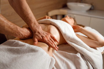 Fototapeta na wymiar Masseur's hands massaging the patient's abdomen. Man makes an anti-cellulite belly massage to a woman