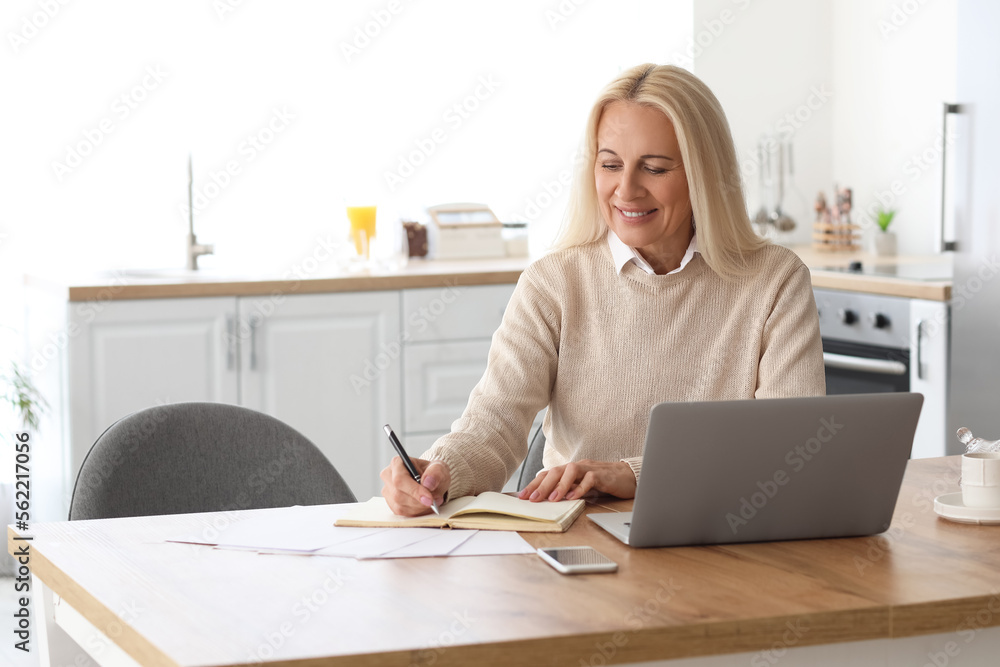 Canvas Prints Mature woman writing in notebook at home