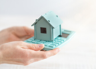 House model and calculator on hands for finance ,selling home and bangking concept