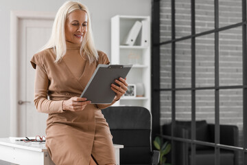 Mature bank manager with clipboard in office