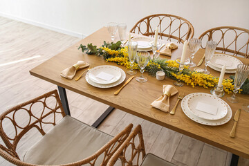 Beautiful table setting with mimosa flowers and candles in room