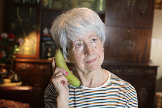 Playful Senior Woman Answering Telephone With A Banana 