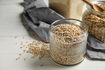 Jar with pearl barley on light wooden table, closeup